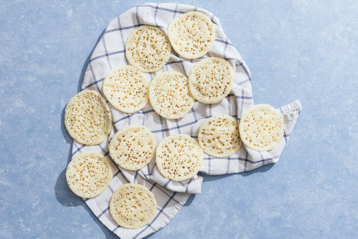Several baghrir spread out on a kitchen towel.