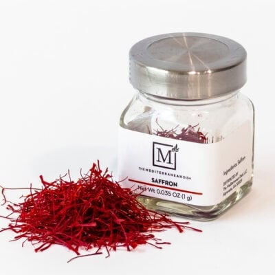 A bottle of saffron from The Mediterranean Dish next to a small pile of the saffron.