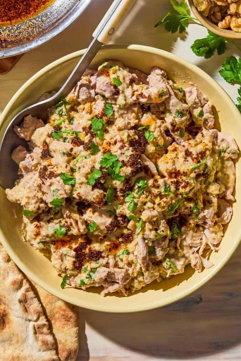 Circassian chicken topped with Aleppo pepper oil in a bowl with a spoon.