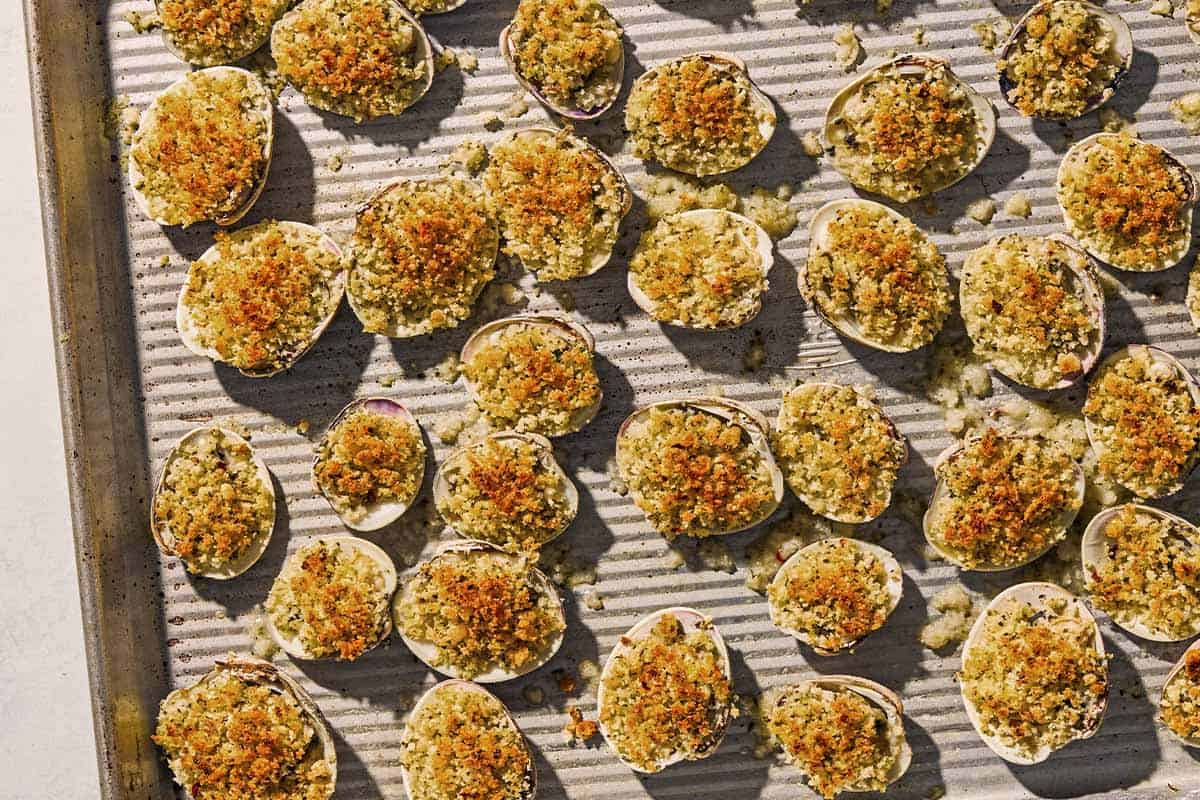 Clams oreganata spread evenly on a sheet pan.