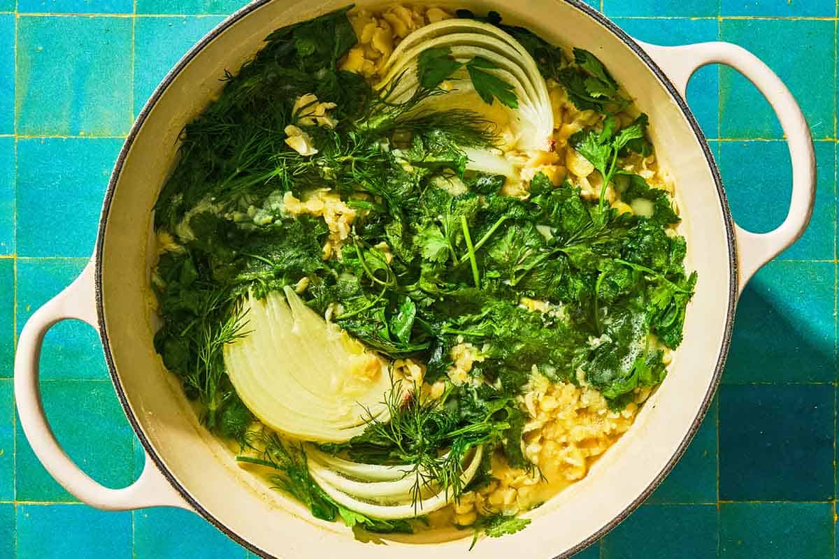 The onion, garlic and herbs simmering with fava beans for the fava bean dip in a pot.