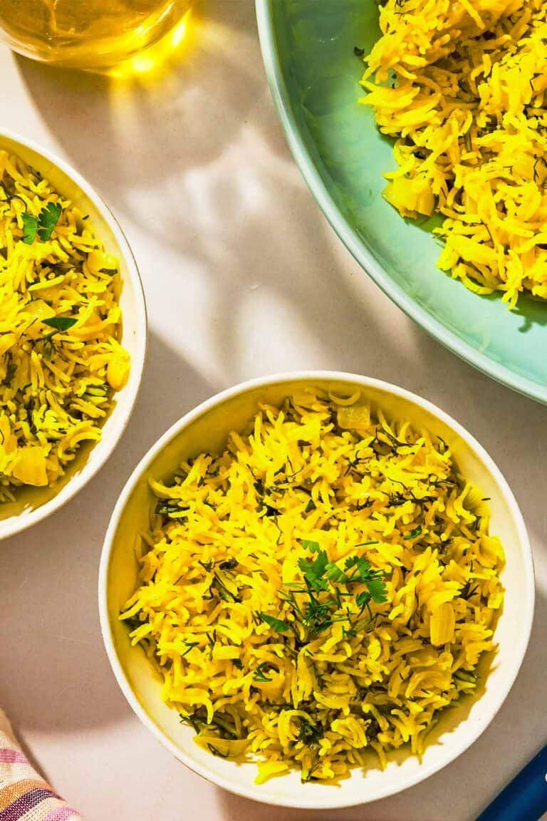 Three bowls of turmeric rice and a bottle of olive oil.