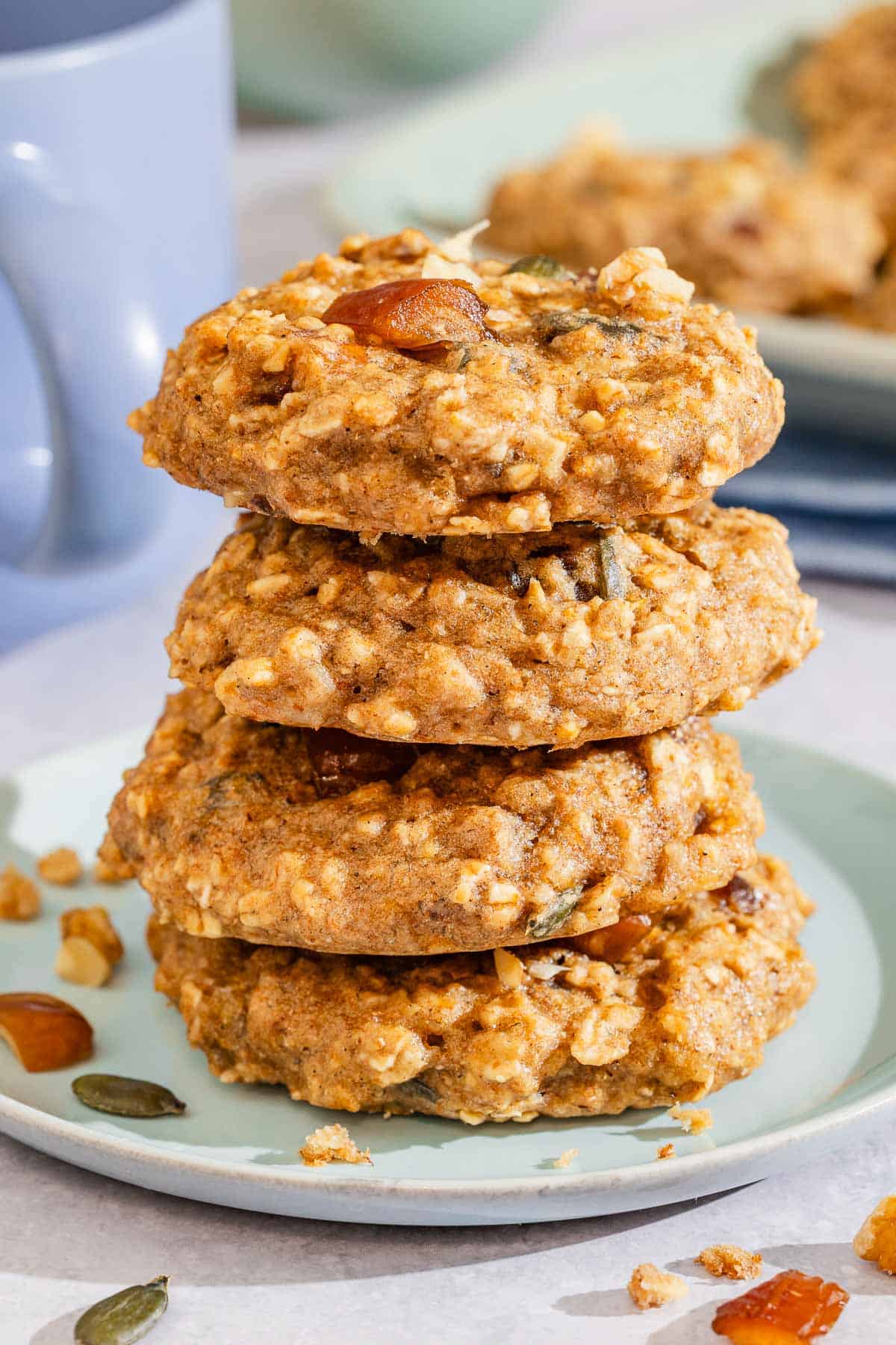 Healthy breakfast cookies made with oats, whole wheat flour, honey, nuts and fruit are stacked on top of eachother on a blue plate.