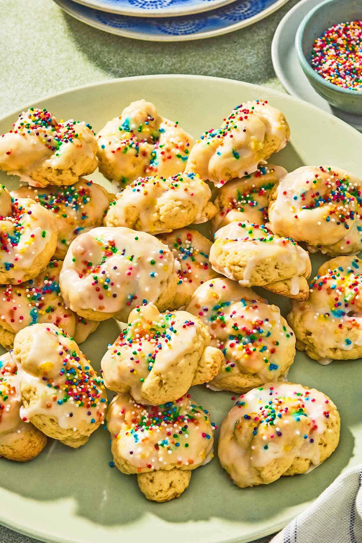 Italian easter cookies on a platter next to a bowl of non-pareils.
