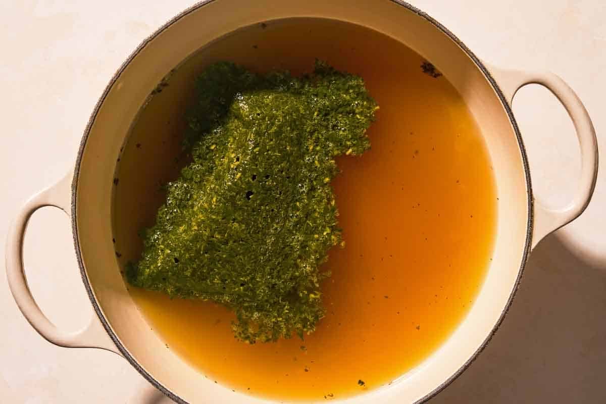 The molokhia with the chicken broth in a pot, just before being stirred together.