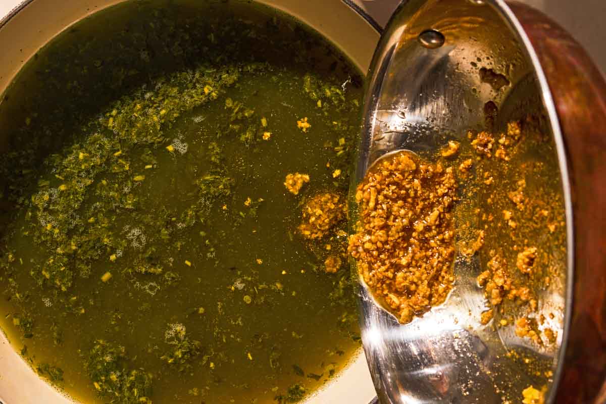 The tasha being added to the molokhia in a pot.