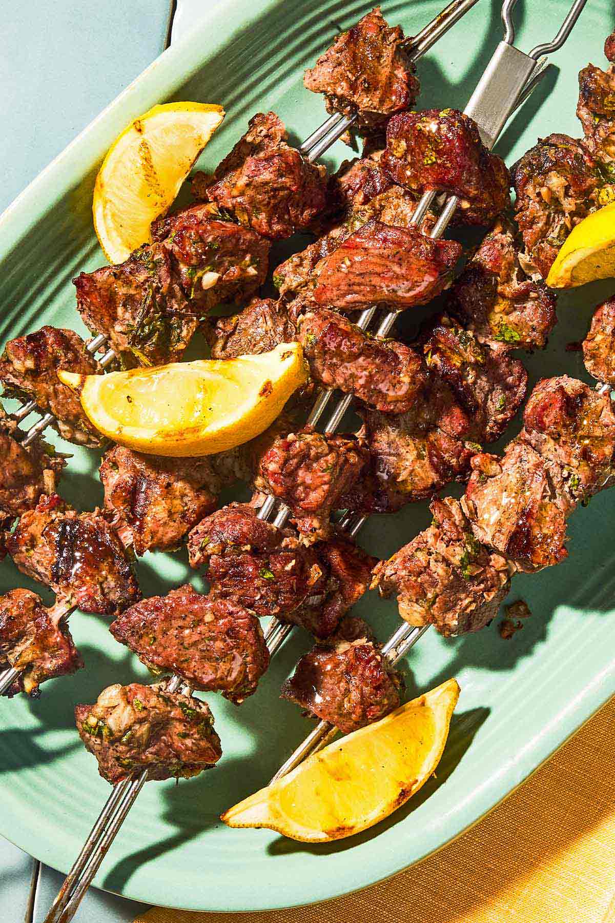 Several juicy lamb kabobs on a platter with lemon wedges perfect for a BBQ.