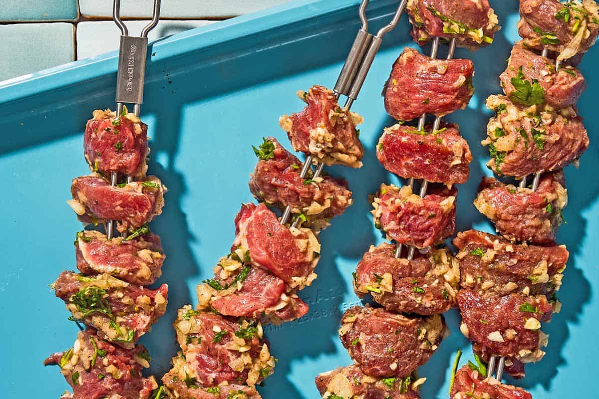 Uncooked lamb kabobs on a platter.