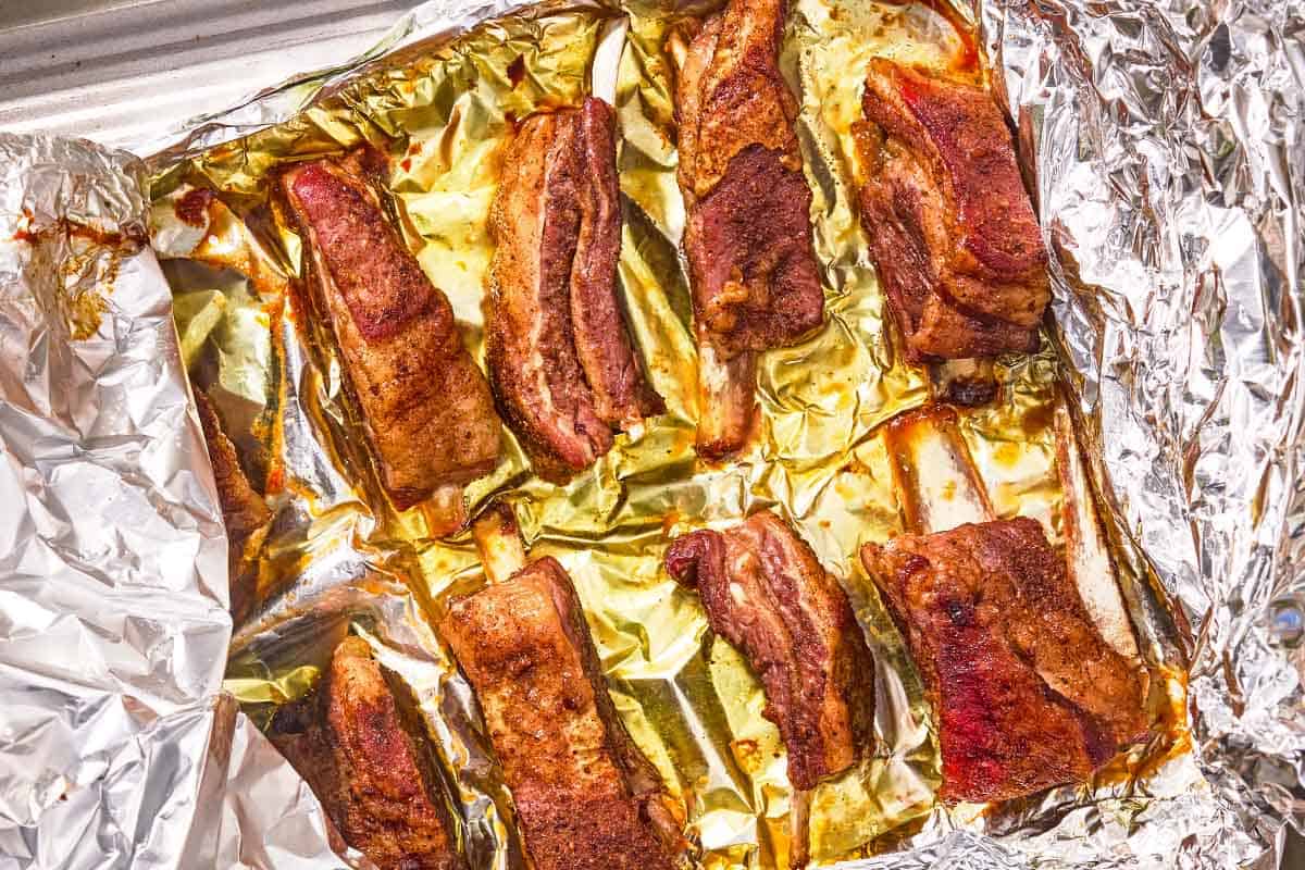 The baked lamb ribs on a foil lined sheet pan.