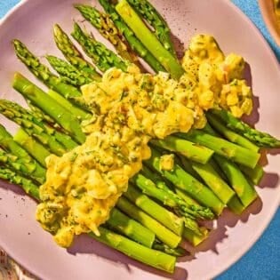 Sauce gribiche over asparagus on a plate.