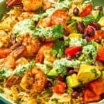 A shrimp bowl with a fork next to a jar of green goddess dressing.