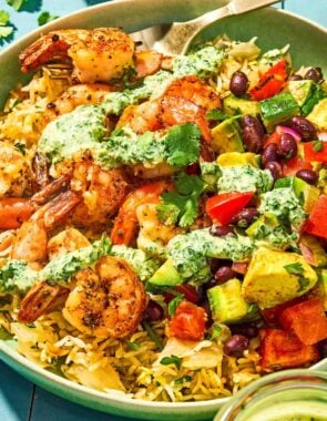 A shrimp bowl with a fork next to a jar of green goddess dressing.