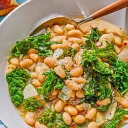A serving of beans and greens in a bowl with a spoon.