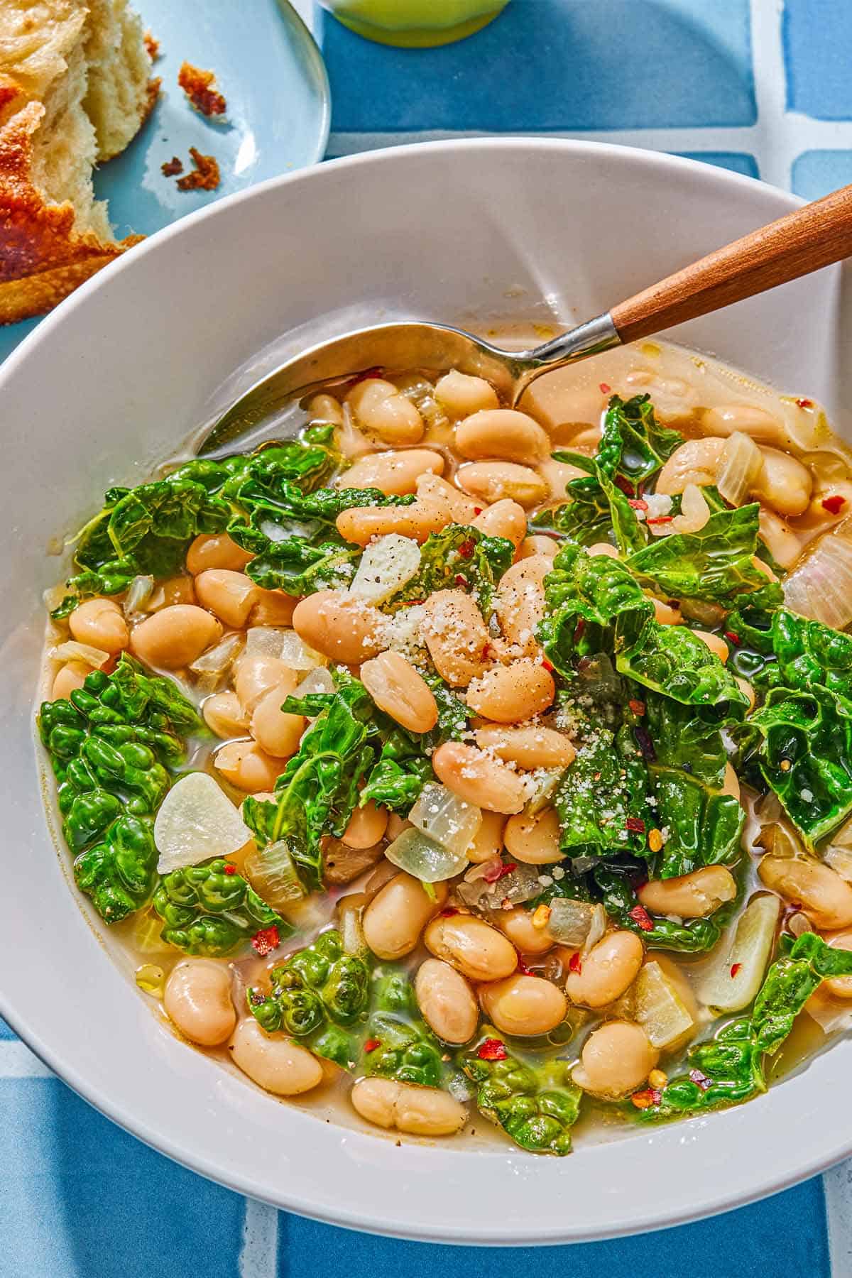 A serving of beans and greens in a bowl with a spoon.