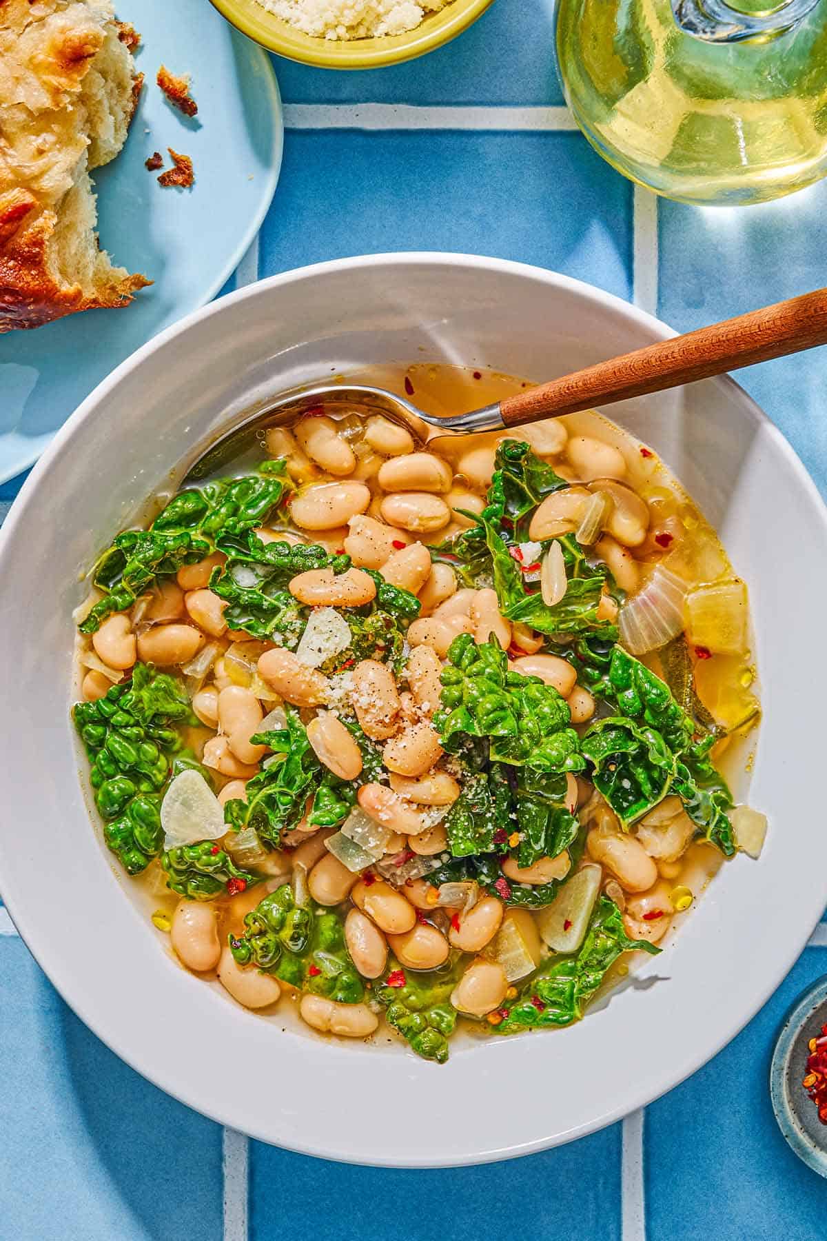 A serving of beans and greens in a bowl with a spoon.