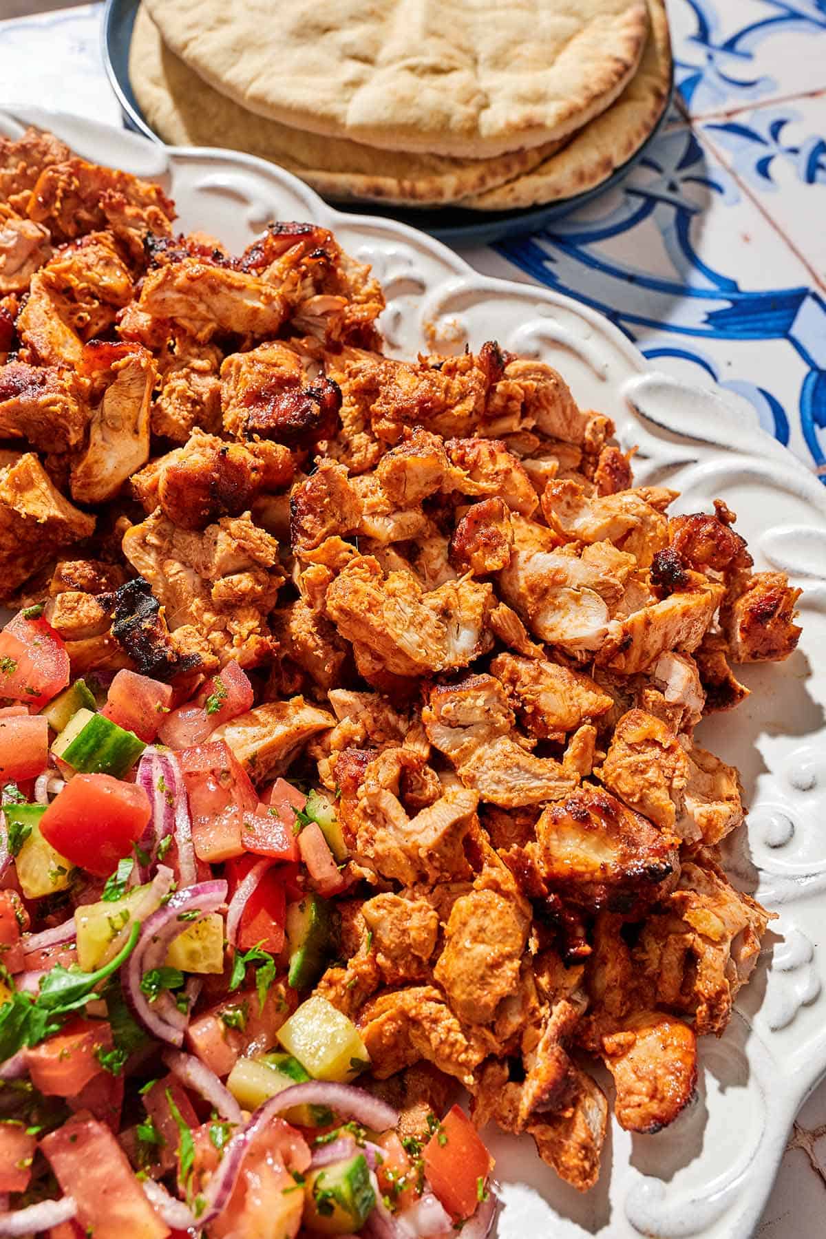 The doner kebab recipe on a platter with a salad next to a plate of pita bread.