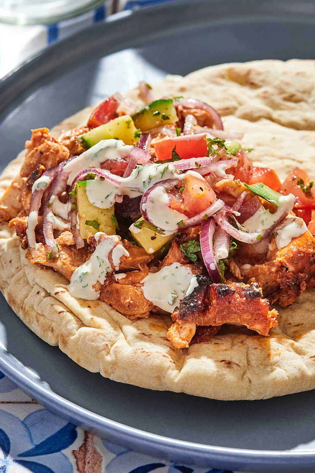 The doner kebab recipe and a tomato cucumber salad on a piece of pita bread drizzled with tahini sauce.