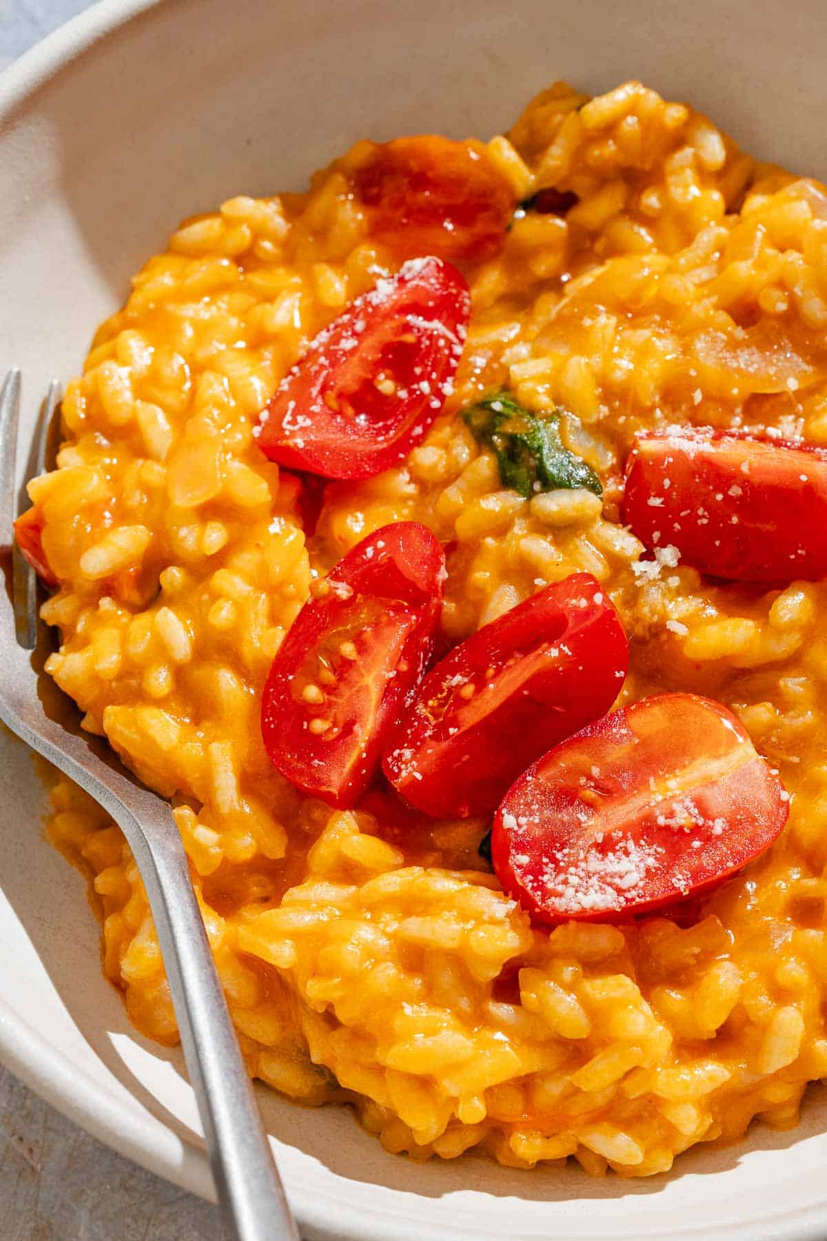Tomato risotto in a bowl with a fork.