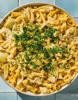 Artichoke pasta in a skillet topped with herbs.