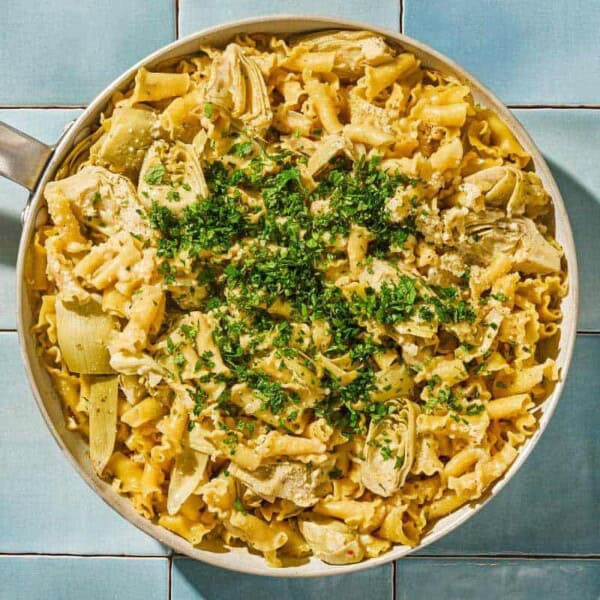 Artichoke pasta in a skillet topped with herbs.