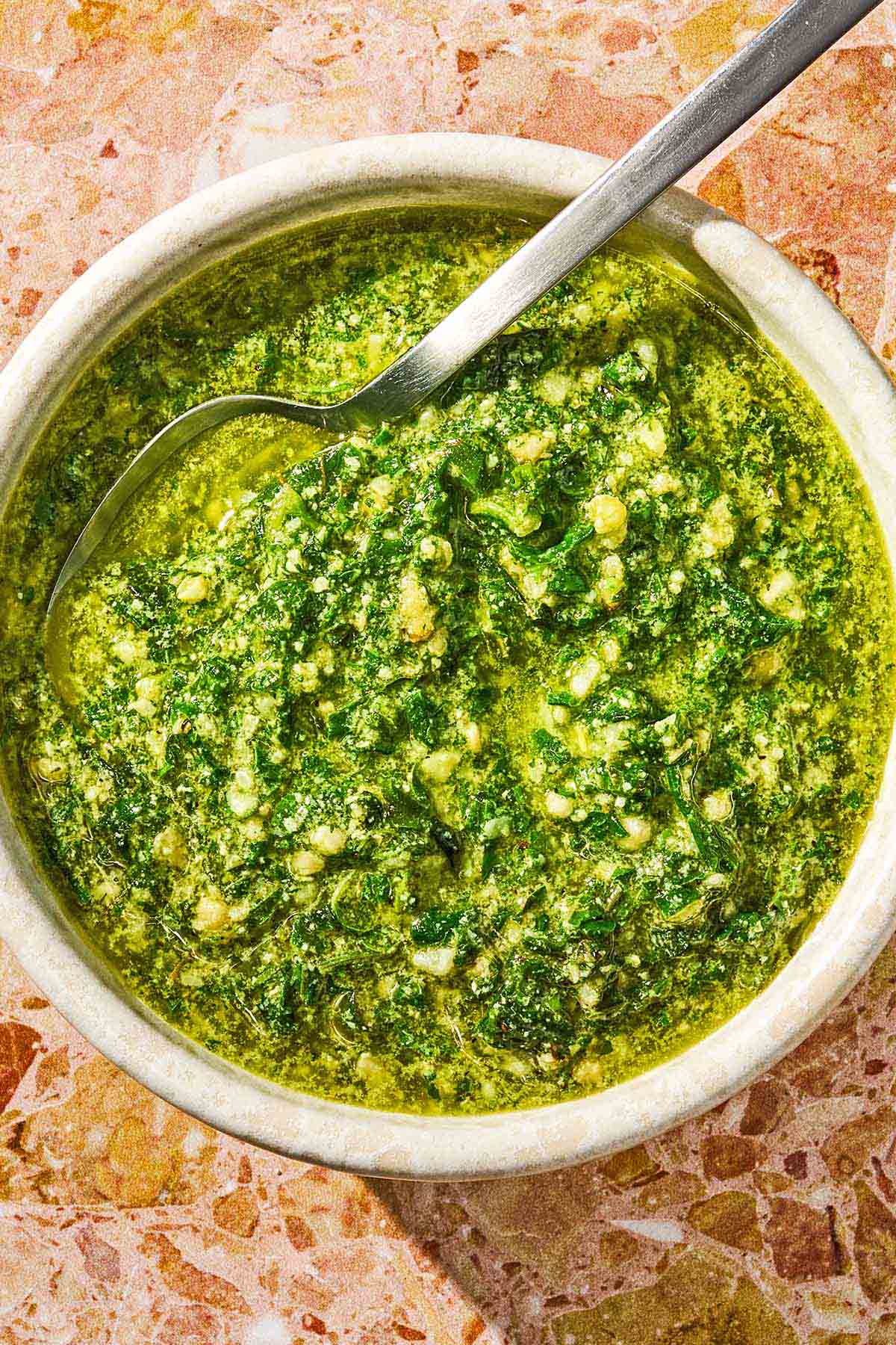 The basil pesto recipe in a bowl with a spoon.