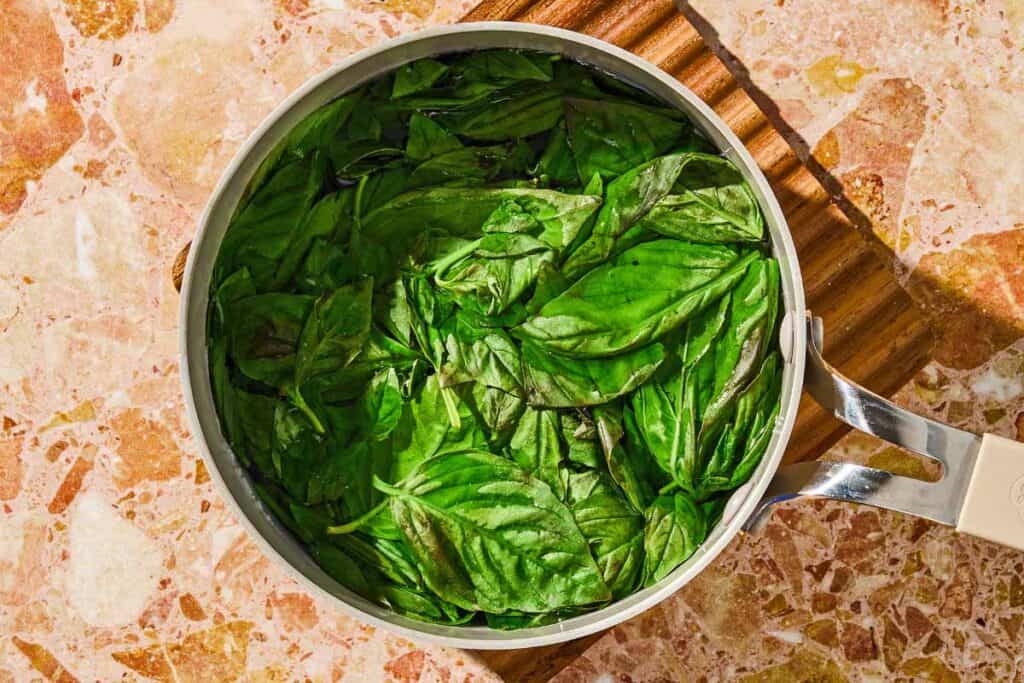 Basil is blanched in a pot.