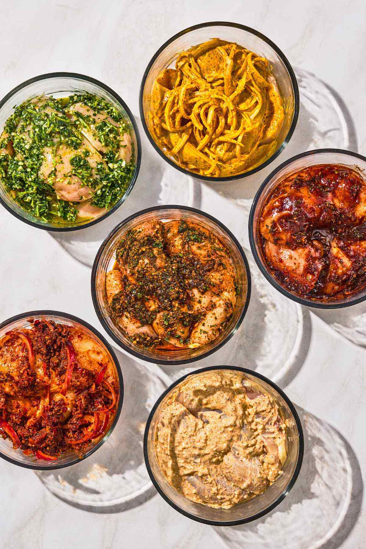 6 different chicken marinade recipes in bowls, each with chicken.