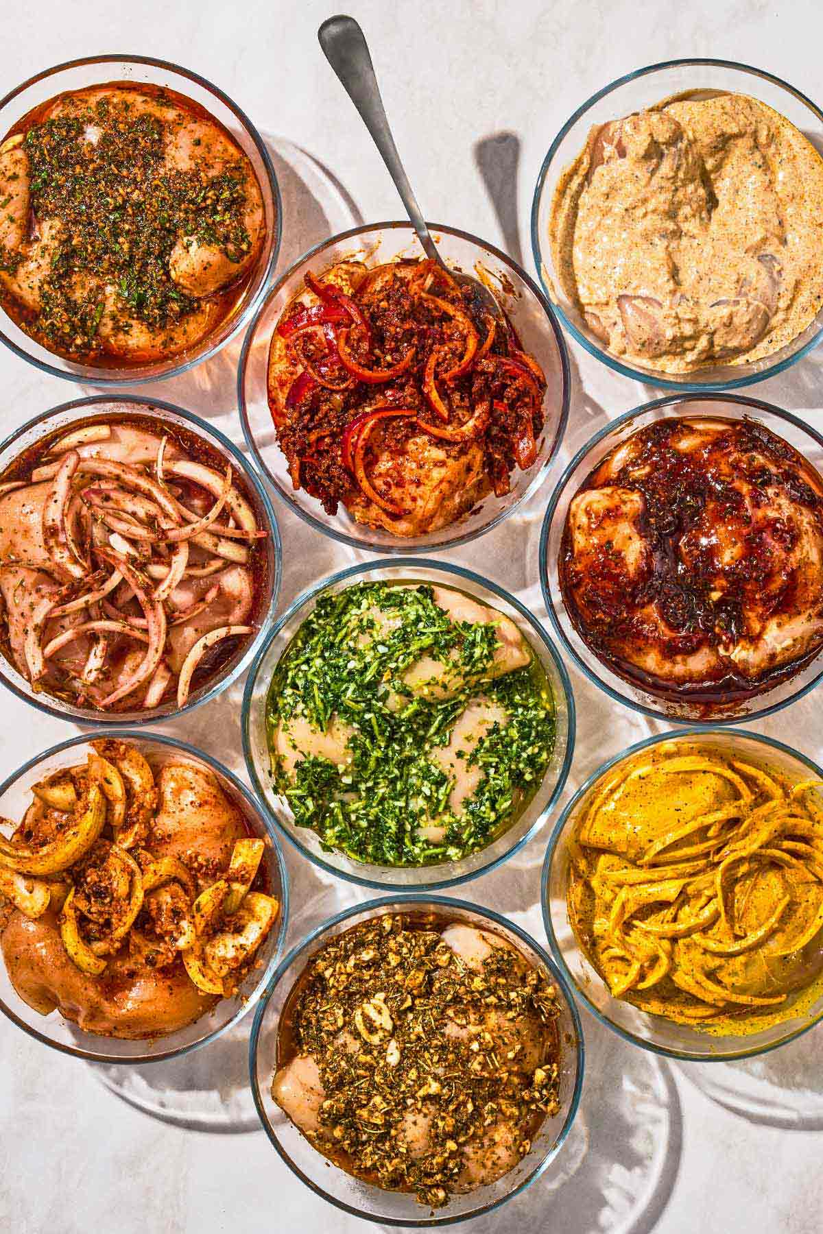 9 different chicken marinade recipes in bowls, each with chicken.