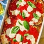 The eggplant parmesan recipe in a baking dish next to a bowl of grated parmesan.