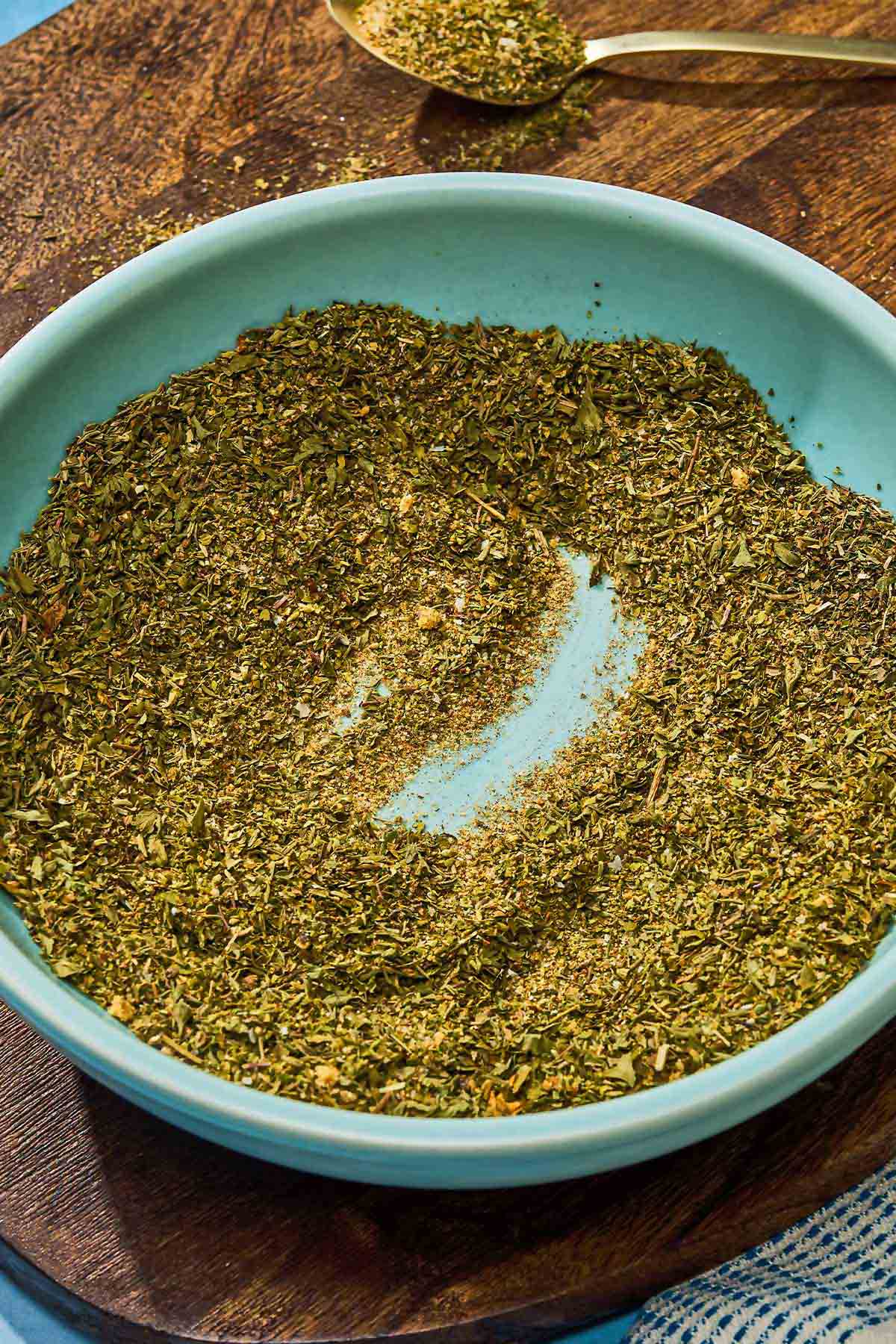 The Greek seasoning in a bowl next to a spoonful of the seasoning.
