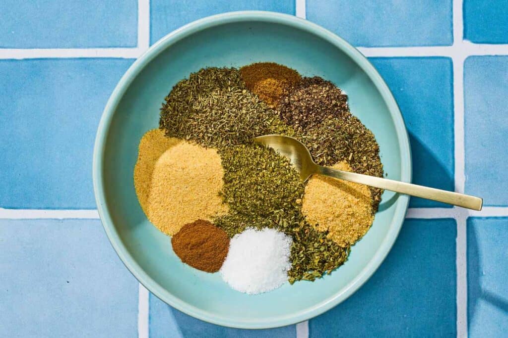 The individual seasonings for the Greek seasoning recipe in a bowl with a spoon just before being mixed together.
