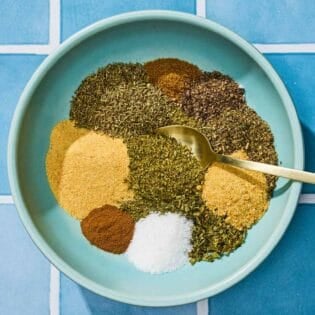 The individual seasonings for the Greek seasoning recipe in a bowl with a spoon just before being mixed together.