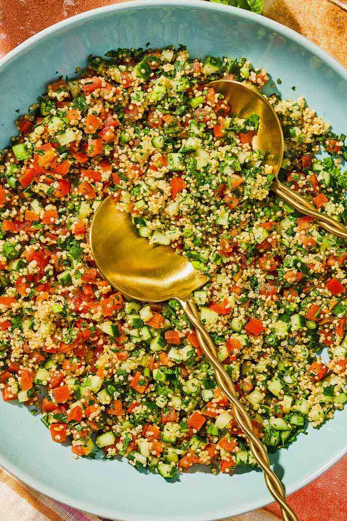 Quinoa tabouli in a serving bowl with serving utensils.