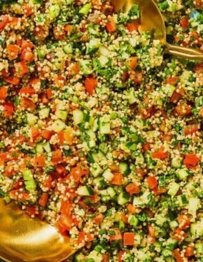 Quinoa tabouli in a serving bowl with serving utensils.