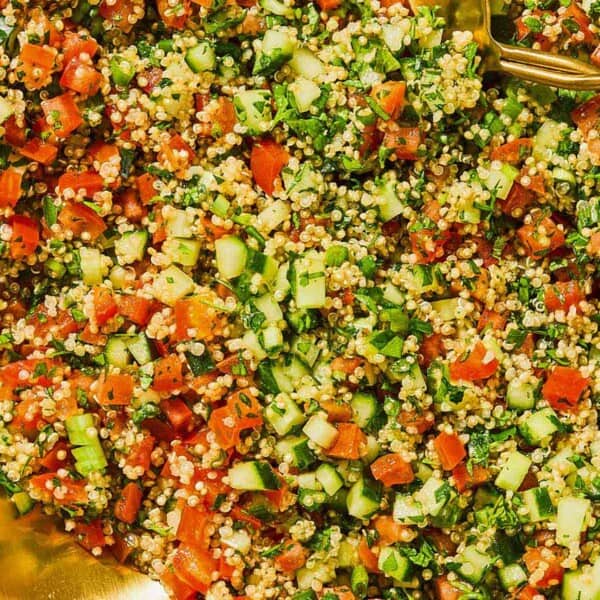 Quinoa tabouli in a serving bowl with serving utensils.