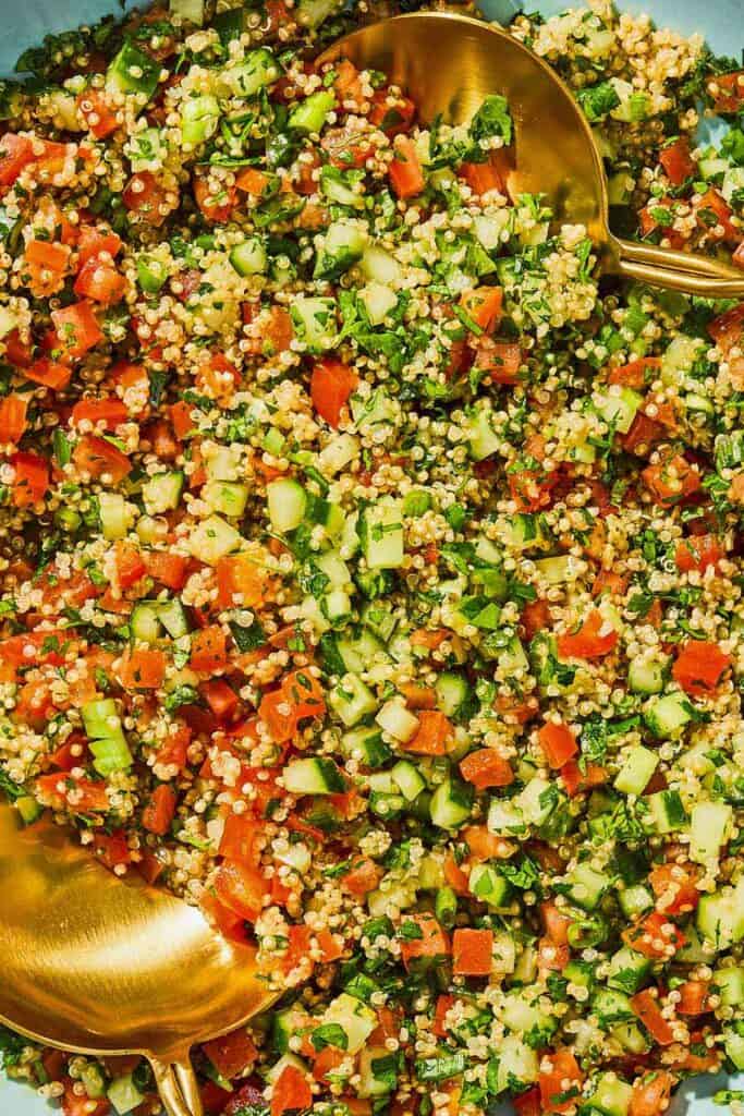 Quinoa tabouli in a serving bowl with serving utensils.