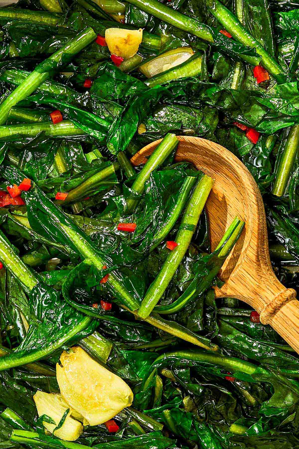 Dandelion greens with a wooden spoon.