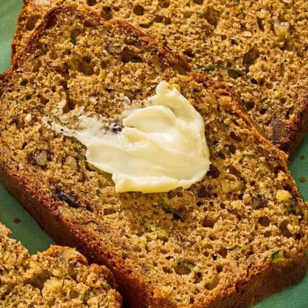 Several slices of zucchini on a platter, one with a dollop of butter.