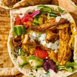 Several chicken shawarma pita sandwiches in a serving bowl.