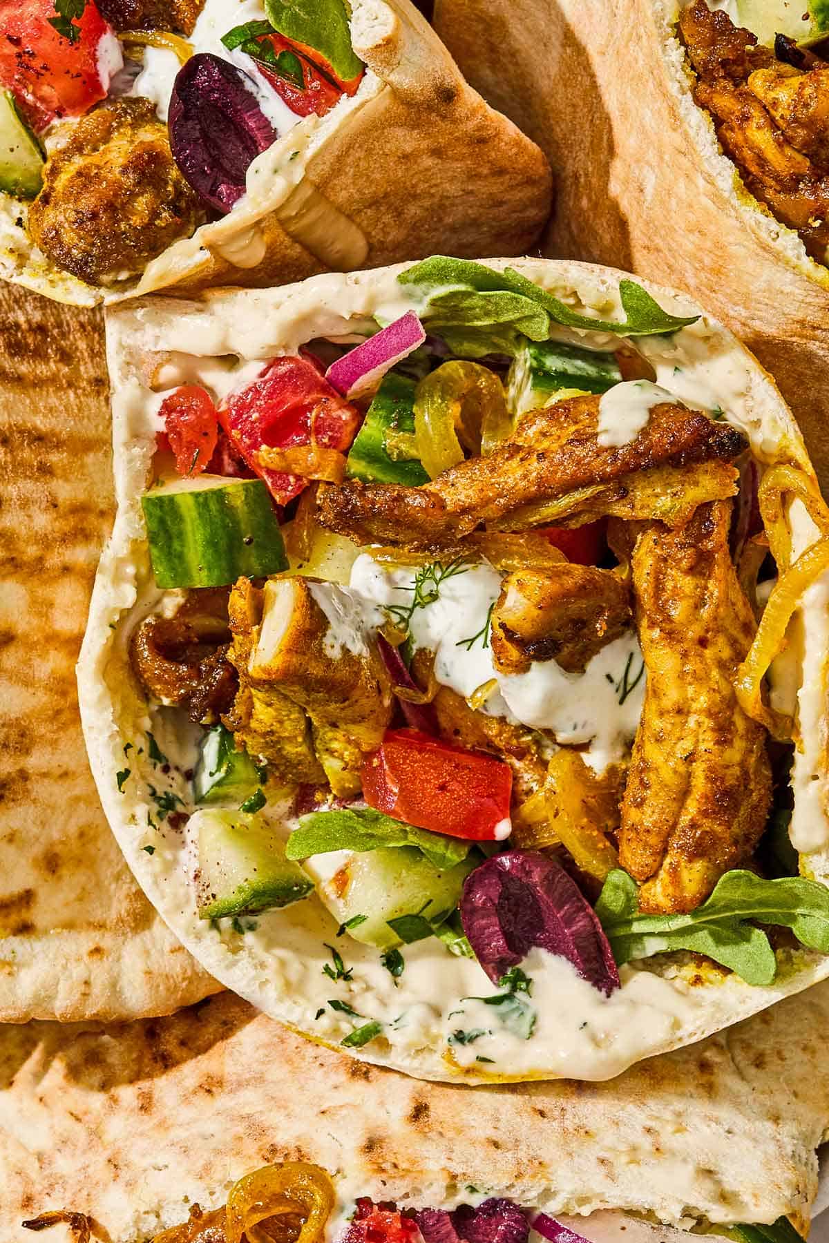 Several chicken shawarma pita sandwiches in a serving bowl.