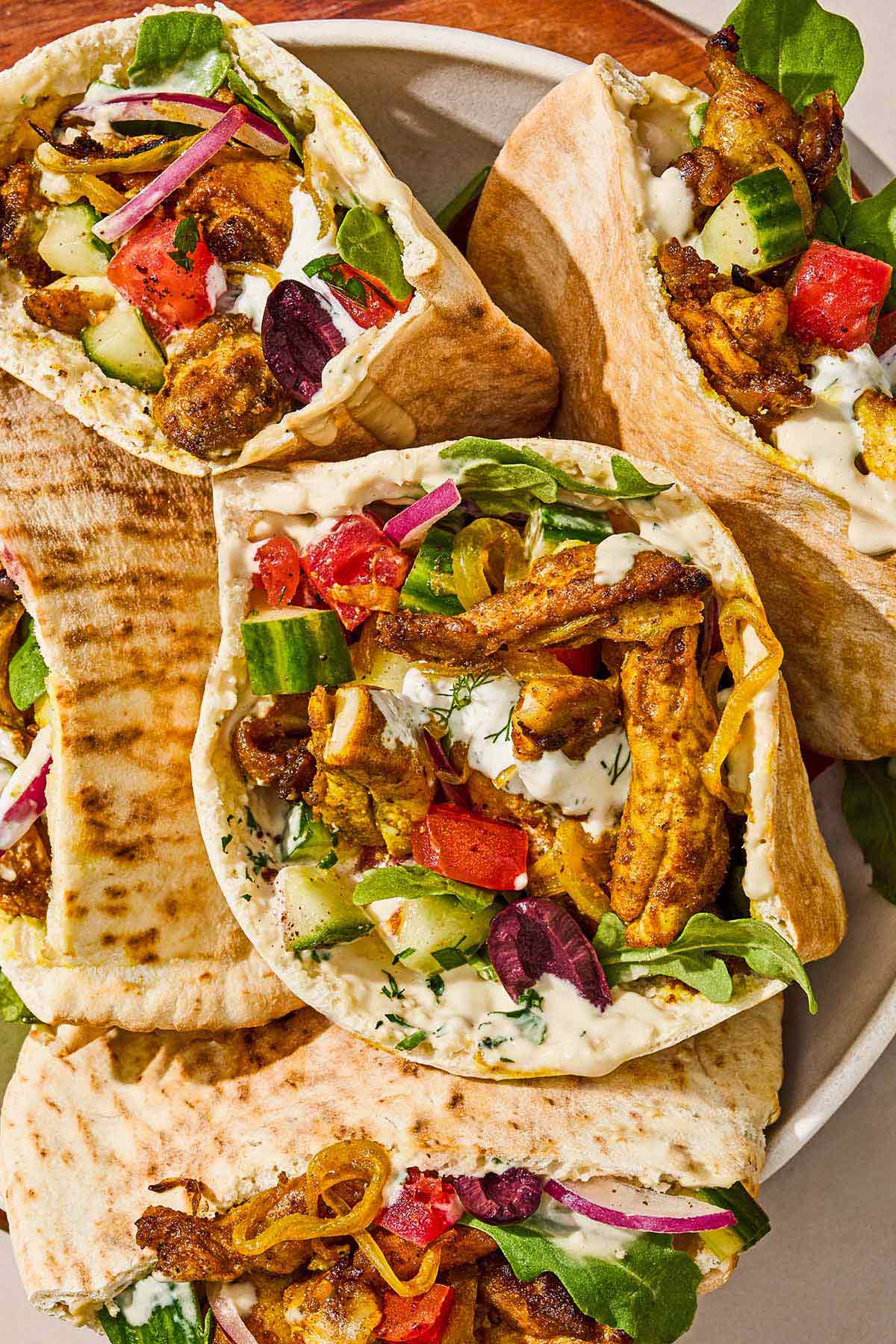 Several chicken shawarma pita sandwiches in a serving bowl.