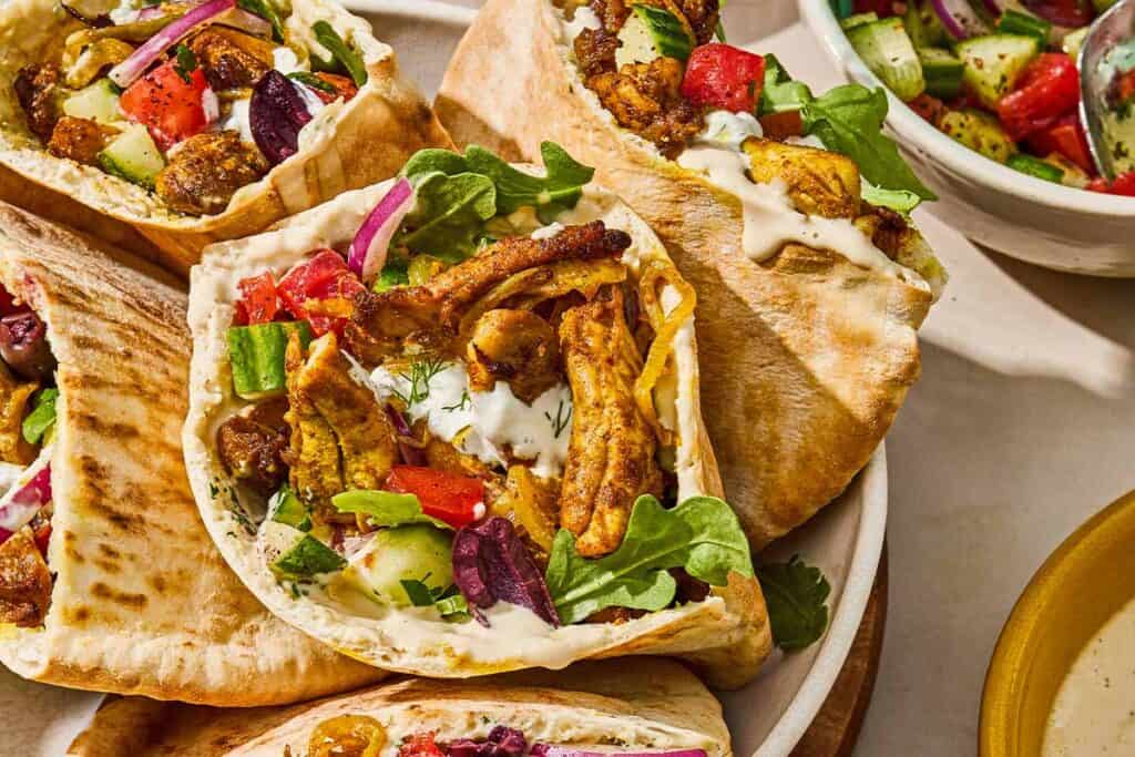 Several chicken shawarma pita sandwiches in a serving bowl for a weeknight dinner chicken recipe.