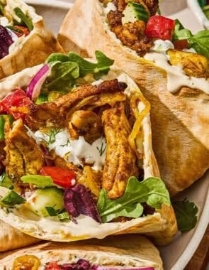 Several chicken shawarma pita sandwiches in a serving bowl for a weeknight dinner chicken recipe.