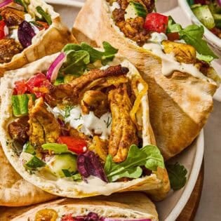 Several chicken shawarma pita sandwiches in a serving bowl for a weeknight dinner chicken recipe.