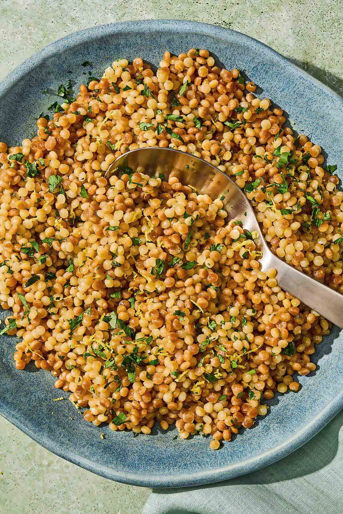 The pearl couscous recipe in a bowl with a spoon.