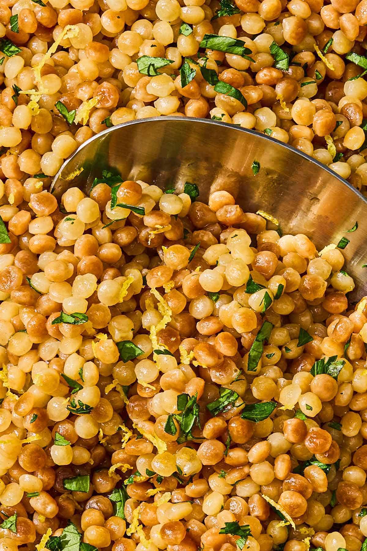 A close up of the pearl couscous recipe with a spoon.