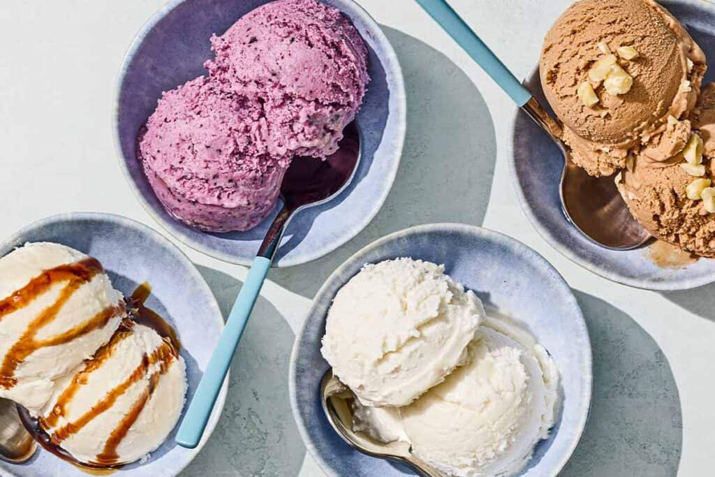 Bowls of tahini, blueberry, vanilla and chocolate hazelnut dairy free ice cream with spoons.
