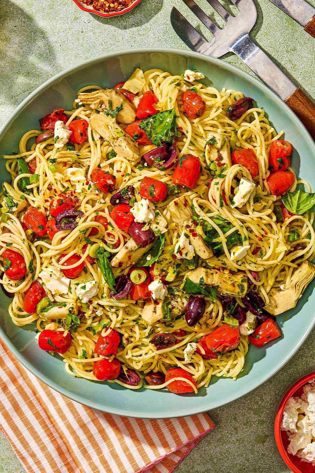 The Mediterranean pasta with olive oil and tomatoes in a blue serving bowl. 