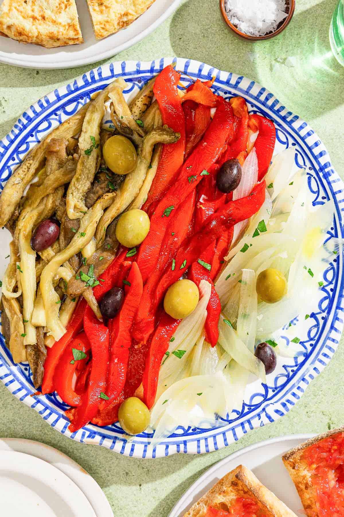 Escalivada topped with parsley and olives on a plate.