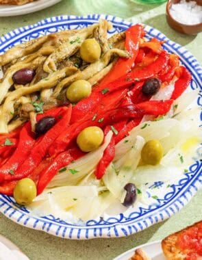 Escalivada topped with parsley and olives on a plate.